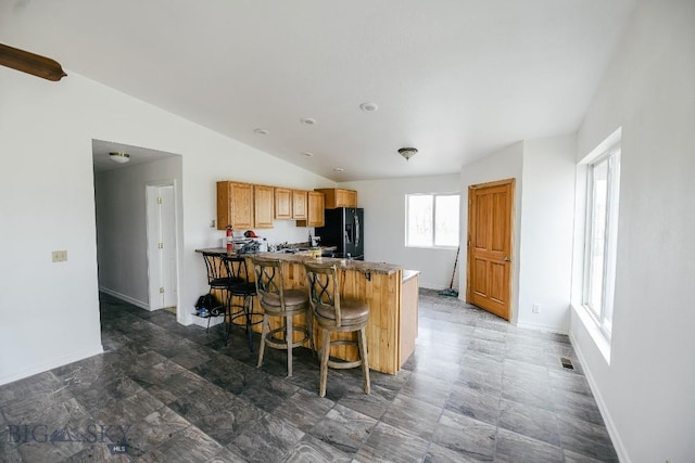 2373 Mt Highway 278, Dillon, MT 59725 - kitchen featuring black refrigerator with ice dispenser, vaulted ceiling, a peninsula, a kitchen bar, and dark countertops