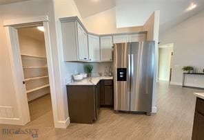17 Durango Trl, Three Forks, MT 59752 - kitchen featuring stainless steel fridge with ice dispenser, light countertops, lofted ceiling, light wood finished floors, and baseboards
