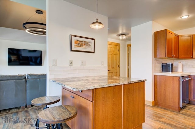 424 E Main St Unit E, Bozeman, MT 59715 - kitchen with backsplash, a peninsula, brown cabinets, light stone counters, and light wood-style flooring