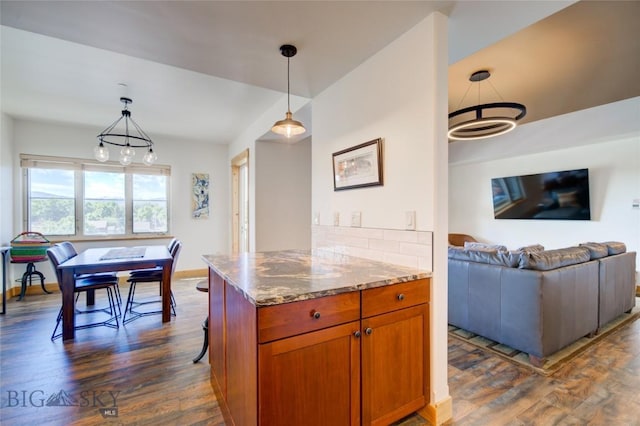 424 E Main St Unit E, Bozeman, MT 59715 - kitchen with dark wood-type flooring, open floor plan, brown cabinetry, stone countertops, and decorative light fixtures