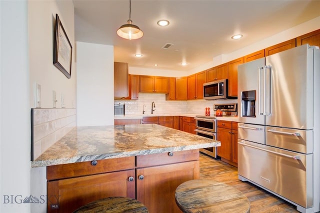 424 E Main St Unit E, Bozeman, MT 59715 - kitchen featuring stainless steel appliances, a peninsula, tasteful backsplash, brown cabinets, and recessed lighting
