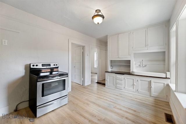 504 4th St, Gardiner, MT 59030 - kitchen with stainless steel range with electric stovetop, light wood-style flooring, white cabinetry, and dark countertops