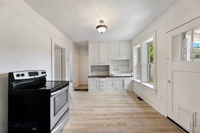 504 4th St, Gardiner, MT 59030 - kitchen with stainless steel range with electric cooktop, white cabinets, light wood-style floors, and dark countertops