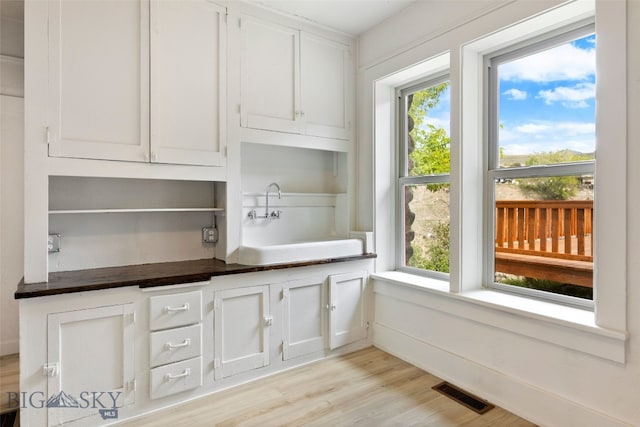 504 4th St, Gardiner, MT 59030 - kitchen with dark countertops, light wood-style flooring, and white cabinets