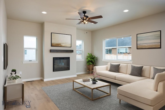1505 Pistolero Way, Belgrade, MT 59714 - living area with a glass covered fireplace, light wood-style flooring, baseboards, ceiling fan, and recessed lighting