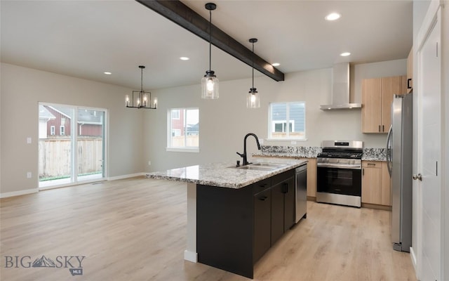 1505 Pistolero Way, Belgrade, MT 59714 - kitchen with appliances with stainless steel finishes, wall chimney range hood, a sink, light wood-style flooring, and a kitchen island with sink