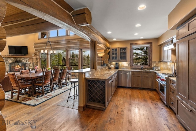 9 Manitou Loop Unit 45E, Big Sky, MT 59716 - kitchen with appliances with stainless steel finishes, a peninsula, a kitchen breakfast bar, a fireplace, and light wood-type flooring