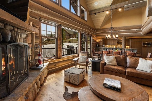 9 Manitou Loop Unit 45E, Big Sky, MT 59716 - sitting room featuring high vaulted ceiling, log walls, a chandelier, a stone fireplace, and wood finished floors