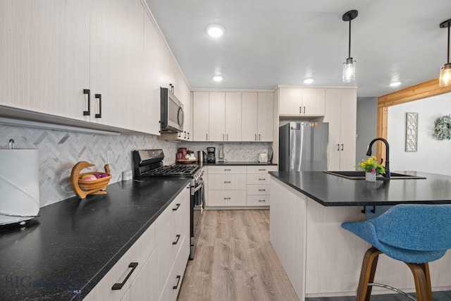 420 N 6th Ave, Bozeman, MT 59715 - kitchen featuring appliances with stainless steel finishes, a sink, a breakfast bar, light wood-style flooring, and dark countertops