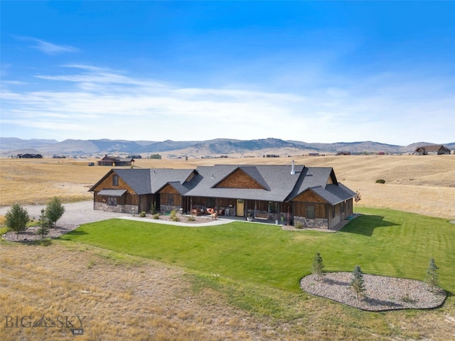 289 Montana Way, Ennis, MT 59729 - rear view of house with stone siding, a mountain view, a yard, and a shingled roof