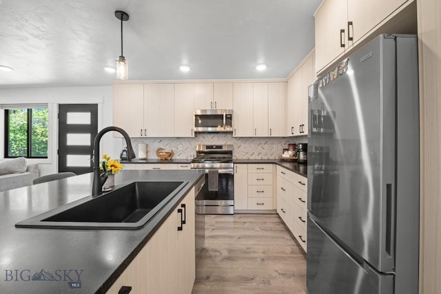 420 N 6th Ave, Bozeman, MT 59715 - kitchen with stainless steel appliances, a sink, dark countertops, light wood-style floors, and pendant lighting