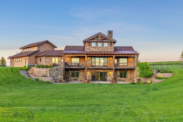 715 Bates Rd, Manhattan, MT 59741 - rear view of house featuring stone siding, a balcony, a chimney, and a patio area