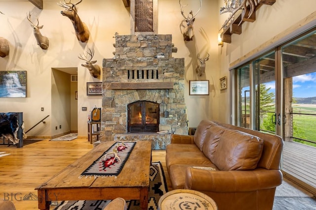 715 Bates Rd, Manhattan, MT 59741 - living room featuring wood finished floors, a stone fireplace, baseboards, and a high ceiling
