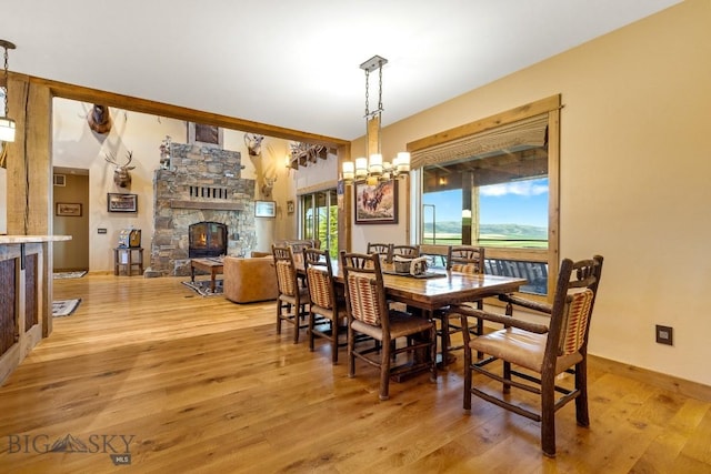 715 Bates Rd, Manhattan, MT 59741 - dining room featuring a fireplace, light wood-type flooring, a chandelier, and baseboards