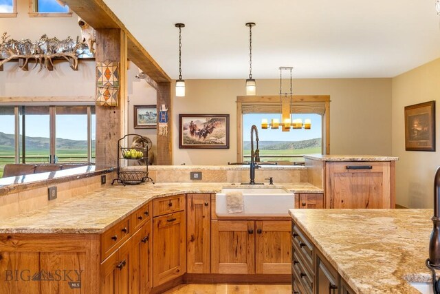 715 Bates Rd, Manhattan, MT 59741 - kitchen featuring light stone counters, a sink, hanging light fixtures, light wood finished floors, and brown cabinets