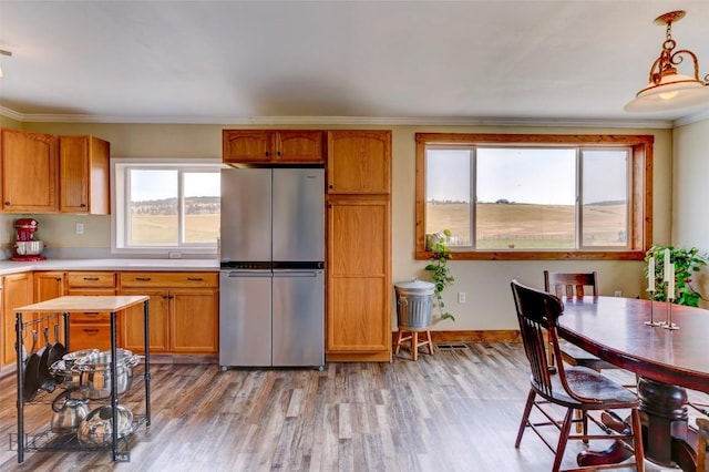 996 Forest Grove Rd, Lewistown, MT 59457 - kitchen featuring freestanding refrigerator, light countertops, light wood-style flooring, crown molding, and brown cabinetry
