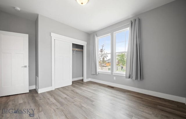 1518 Deadwood Loop, Belgrade, MT 59714 - unfurnished bedroom featuring wood finished floors, a closet, and baseboards