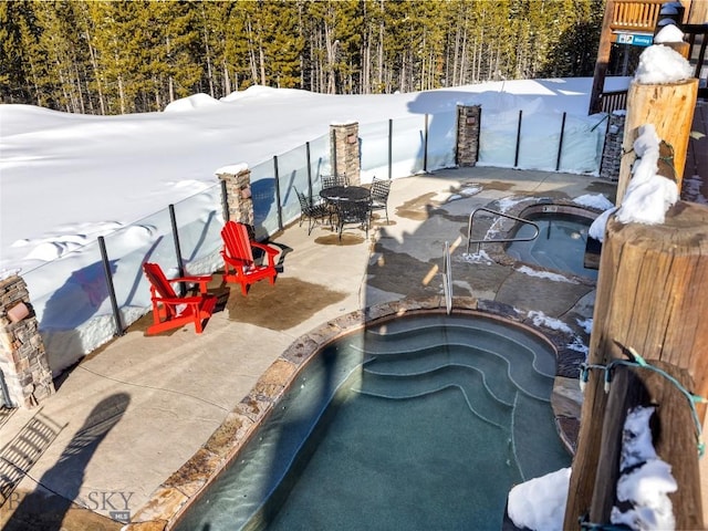 18 Upper Cascade Ridge Rd Unit 18, Big Sky, MT 59716 - snow covered pool with an in-ground hot tub, a view of trees, and a patio