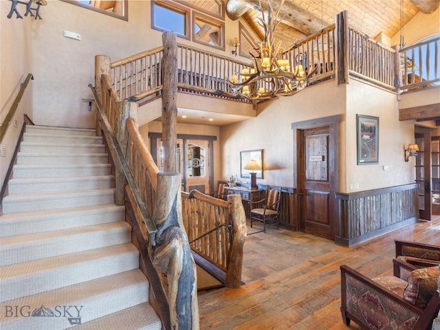18 Upper Cascade Ridge Rd Unit 18, Big Sky, MT 59716 - staircase with high vaulted ceiling, hardwood / wood-style flooring, wood ceiling with exposed beams, a chandelier, and a wainscoted wall