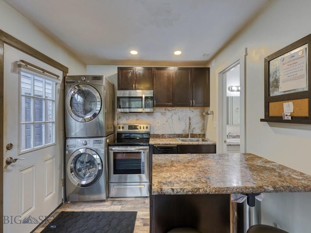 21 Sitting Bull Unit 1220, Big Sky, MT 59716 - kitchen with stainless steel appliances, stacked washer / dryer, a sink, dark brown cabinets, and light wood-style flooring