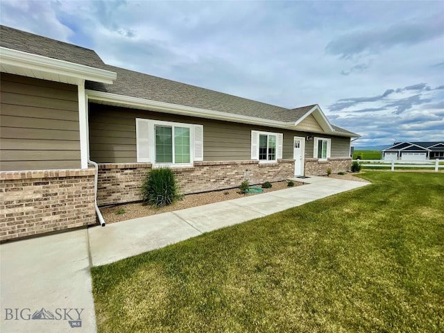 121 Ridge Ct, Dillon, MT 59725 - view of front of home featuring brick siding, a front yard, and roof with shingles