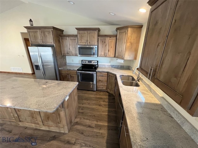 121 Ridge Ct, Dillon, MT 59725 - kitchen with appliances with stainless steel finishes, a sink, vaulted ceiling, dark wood-type flooring, and light stone counters