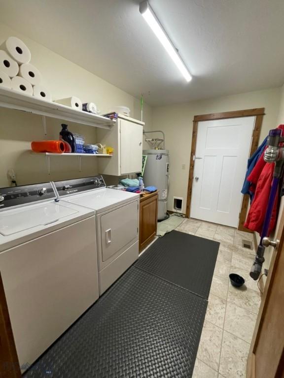 121 Ridge Ct, Dillon, MT 59725 - laundry area featuring water heater, washing machine and dryer, cabinet space, and light tile patterned flooring