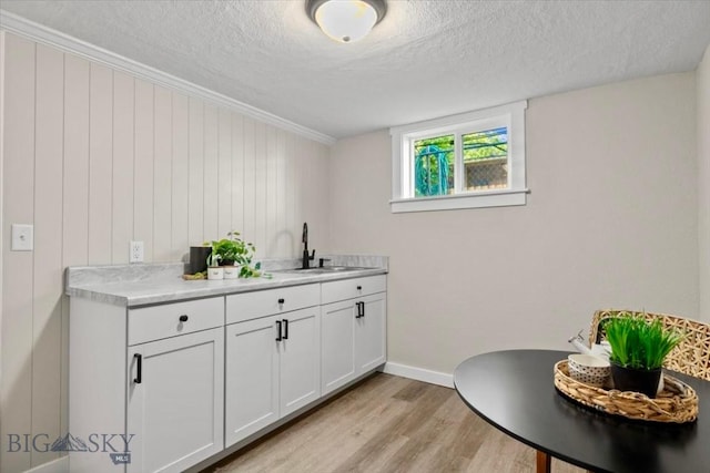 643 Parkhill, Billings, MT 59102 - bar area featuring a textured ceiling, a sink, light wood finished floors, crown molding, and baseboards