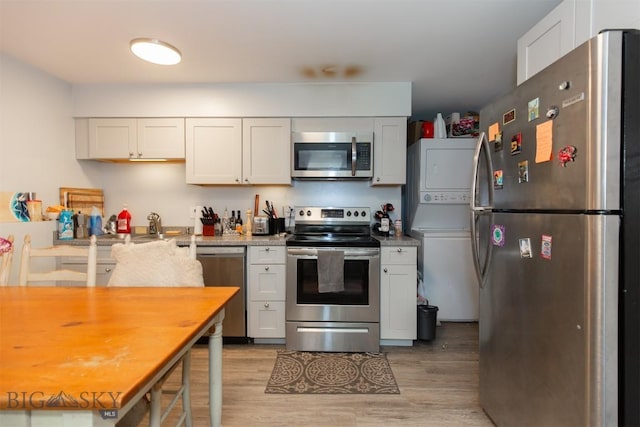 504 N 19th Ave, Bozeman, MT 59718 - kitchen with appliances with stainless steel finishes, stacked washer / dryer, light wood-style flooring, and white cabinets