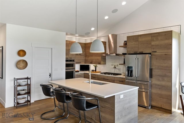 646 Arrow Trl, Bozeman, MT 59718 - kitchen featuring stainless steel appliances, wall chimney exhaust hood, a sink, light wood-style floors, and vaulted ceiling