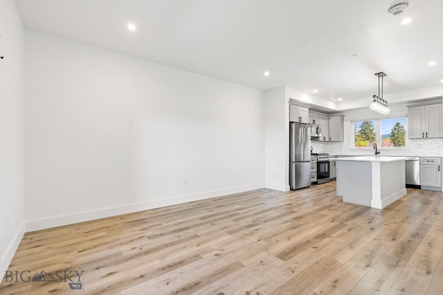 1704 W Lincoln Unit 5B, Bozeman, MT 59715 - kitchen featuring appliances with stainless steel finishes, decorative backsplash, light countertops, light wood-style floors, and recessed lighting