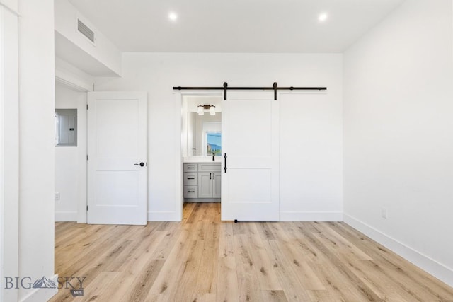 1704 W Lincoln Unit 5B, Bozeman, MT 59715 - unfurnished bedroom with a barn door, electric panel, light wood-style floors, recessed lighting, and ensuite bathroom