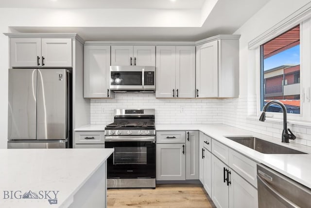 1704 W Lincoln Unit 5B, Bozeman, MT 59715 - kitchen with stainless steel appliances, light countertops, backsplash, light wood-type flooring, and recessed lighting