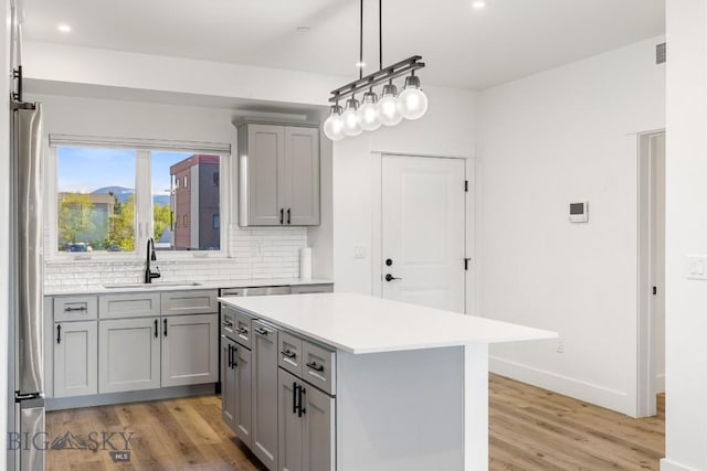 1704 W Lincoln Unit 5B, Bozeman, MT 59715 - kitchen featuring gray cabinets, a sink, light wood finished floors, light countertops, and tasteful backsplash