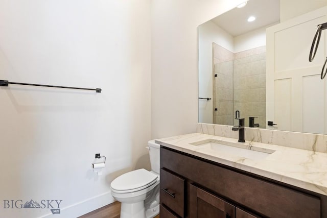 1609 Wyatt Earp Ct, Belgrade, MT 59714 - bathroom featuring vanity, toilet, wood finished floors, a tile shower, and baseboards
