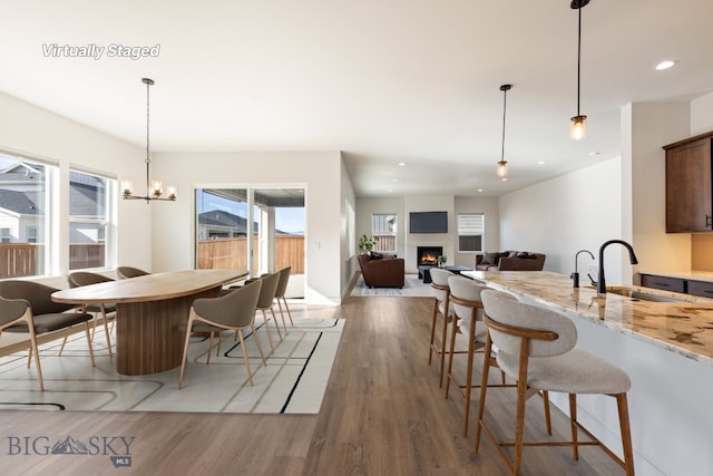 1609 Wyatt Earp Ct, Belgrade, MT 59714 - dining space with healthy amount of natural light, a warm lit fireplace, light wood finished floors, recessed lighting, and a chandelier