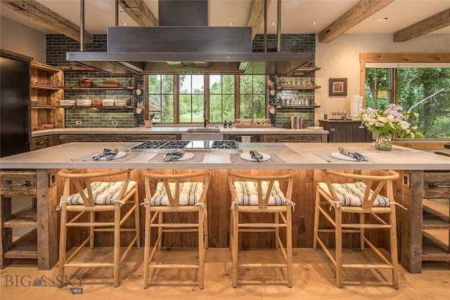 5933 Monforton School Rd, Bozeman, MT 59718 - bar area with island exhaust hood, beamed ceiling, stainless steel gas stovetop, plenty of natural light, and a sink