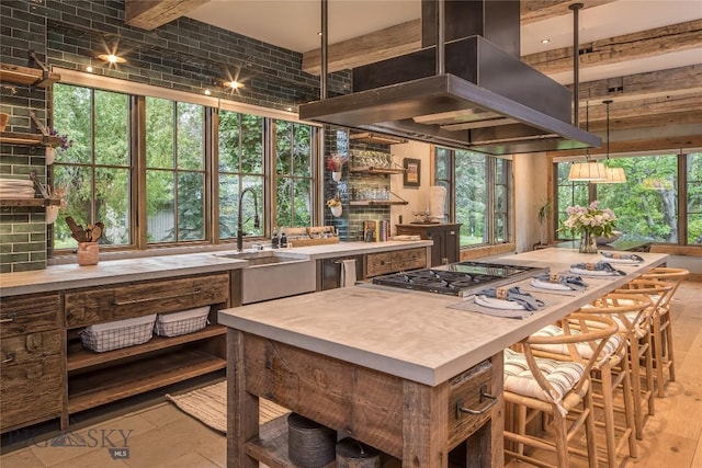 5933 Monforton School Rd, Bozeman, MT 59718 - kitchen with wall chimney exhaust hood, stainless steel gas cooktop, a sink, light countertops, and a center island