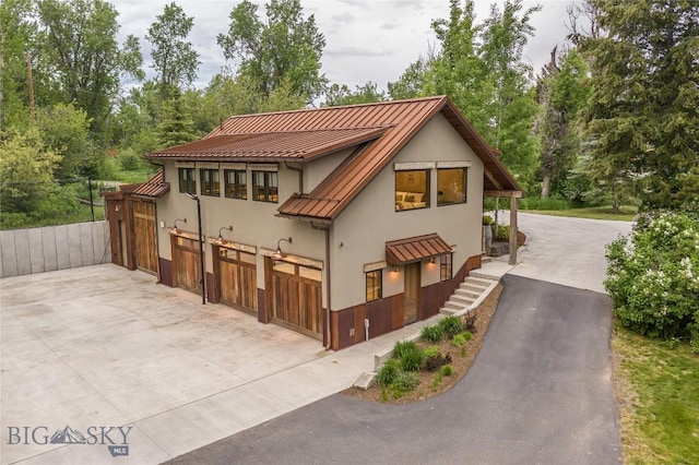 5933 Monforton School Rd, Bozeman, MT 59718 - view of front facade featuring stucco siding, a standing seam roof, concrete driveway, and metal roof