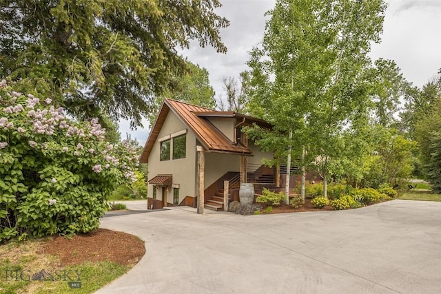 5933 Monforton School Rd, Bozeman, MT 59718 - view of front facade featuring a standing seam roof, driveway, metal roof, stucco siding, and an attached garage