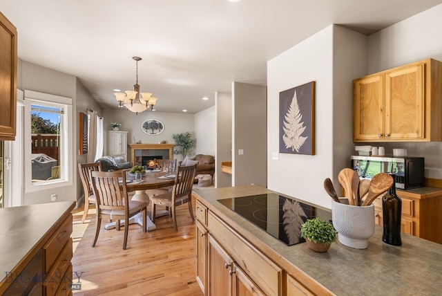 126 Pathfinder Trl, Bozeman, MT 59718 - kitchen with black electric cooktop, light wood finished floors, stainless steel microwave, a chandelier, and decorative light fixtures