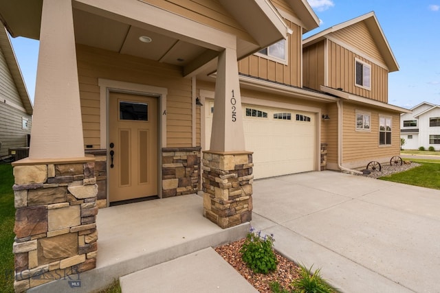 1025 Advance Dr, Bozeman, MT 59718 - view of exterior entry featuring board and batten siding, a garage, driveway, and stone siding