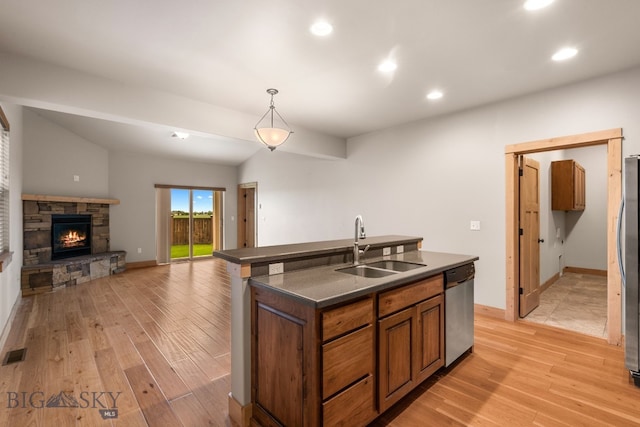 1025 Advance Dr, Bozeman, MT 59718 - kitchen featuring dark countertops, stainless steel appliances, light wood-style flooring, a center island with sink, and brown cabinets