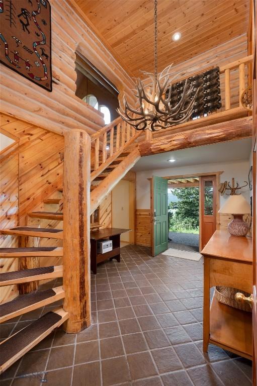 2415 Crazy Horse Rd, Big Sky, MT 59716 - stairs featuring a chandelier, wood ceiling, a high ceiling, a wainscoted wall, and rustic walls