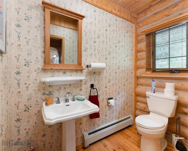 2415 Crazy Horse Rd, Big Sky, MT 59716 - bathroom with a baseboard radiator, wood finished floors, toilet, log walls, and wallpapered walls