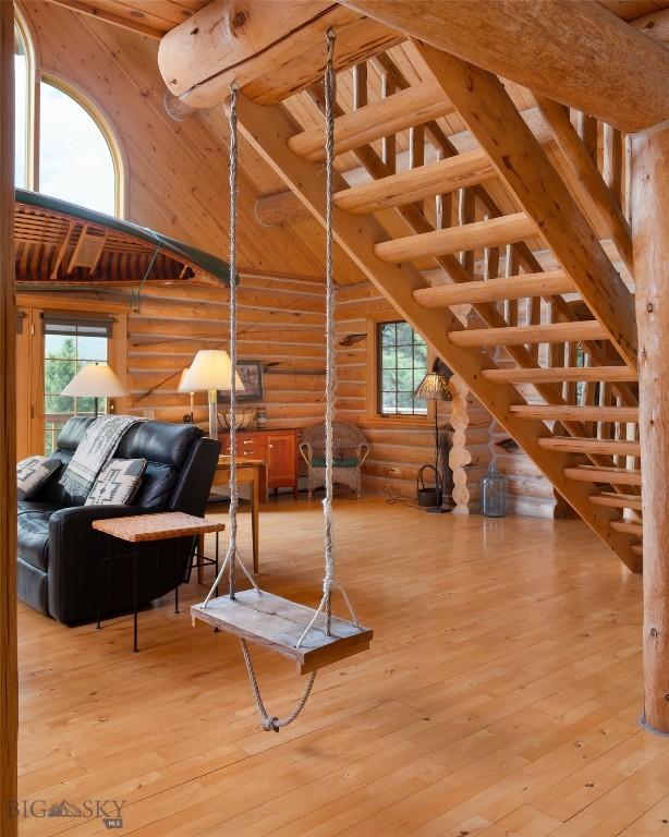 2415 Crazy Horse Rd, Big Sky, MT 59716 - living area with log walls, healthy amount of natural light, wooden ceiling with exposed beams, hardwood / wood-style floors, and high vaulted ceiling