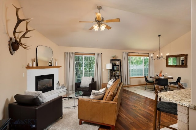 56 Green Belt Dr, Belgrade, MT 59714 - living area featuring lofted ceiling, healthy amount of natural light, a chandelier, a glass covered fireplace, and wood finished floors