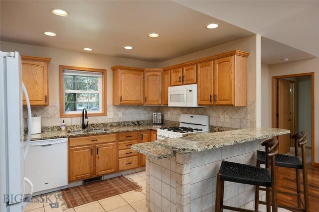 56 Green Belt Dr, Belgrade, MT 59714 - kitchen featuring white appliances, a sink, a peninsula, light stone counters, and recessed lighting