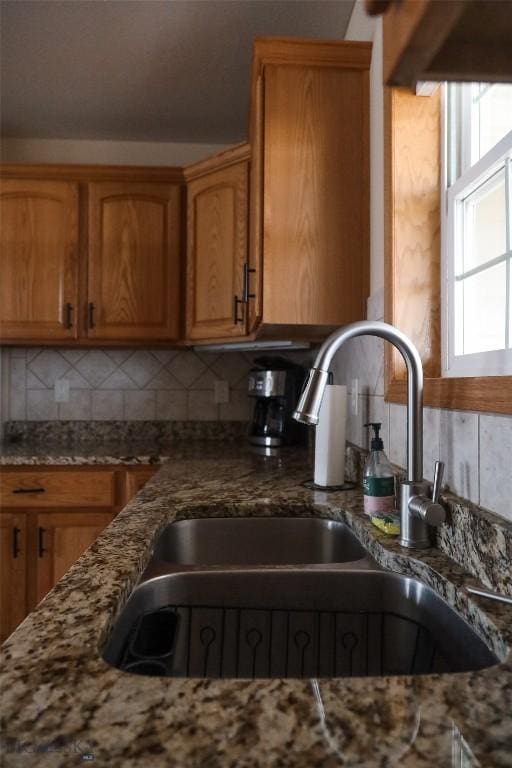 56 Green Belt Dr, Belgrade, MT 59714 - kitchen featuring a sink, stone countertops, backsplash, and brown cabinets