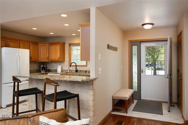 56 Green Belt Dr, Belgrade, MT 59714 - kitchen featuring freestanding refrigerator, a sink, backsplash, light stone countertops, and a kitchen bar